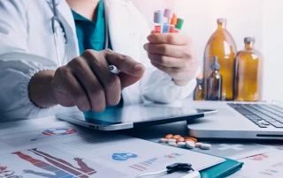 Pharma professional reviewing GMP compliance data and lab samples for a quality audit.